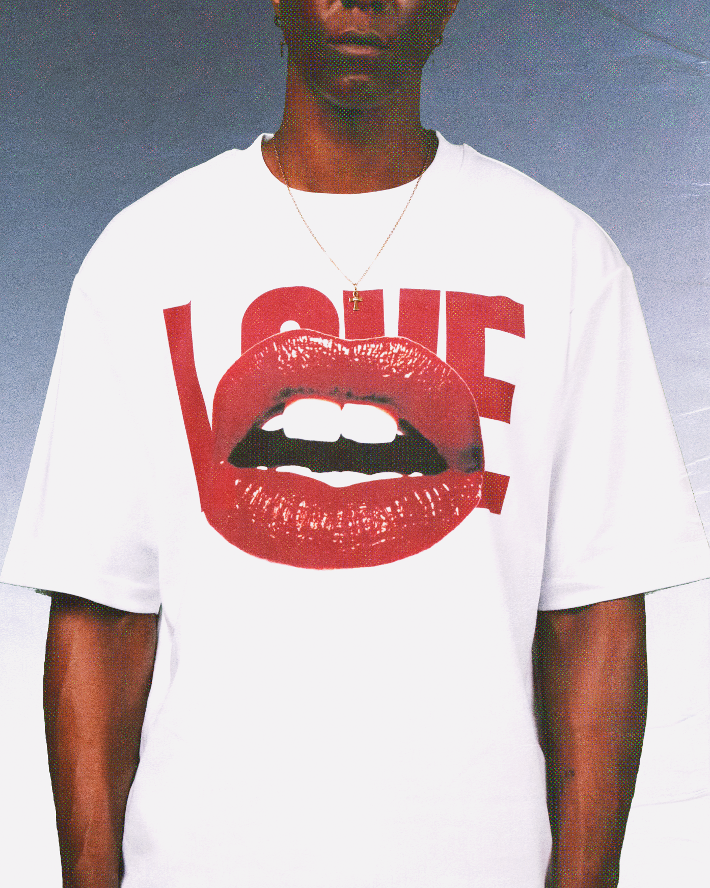 A black man at the forefront of fashion, shooting a look featuring a bright red graphic T-shirt adorned with red lips, a trendy summer streetwear style, and a vacation vibe.